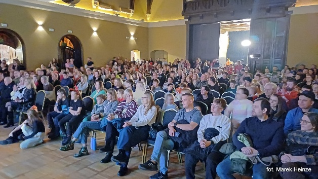 Pełna sala widzów podczas spotkania w zabytkowej auli