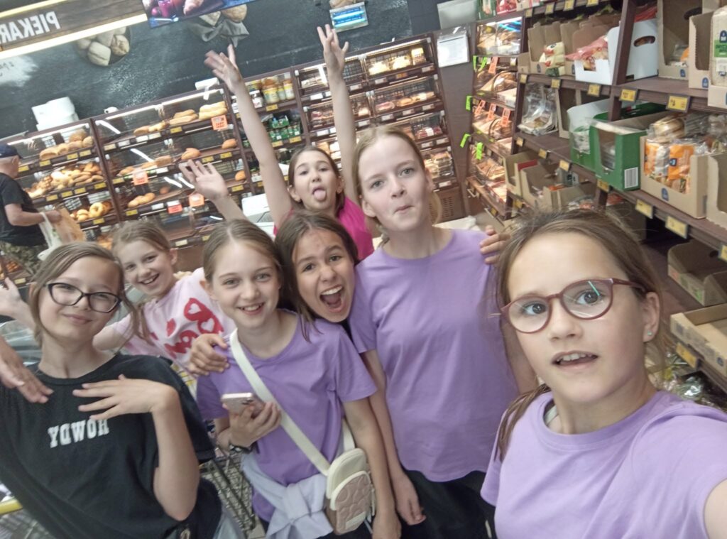 Dziewczynki w fioletowych koszulkach pozują do selfie w sklepie